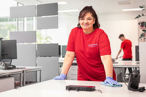 Dussmann employee from the cleaning services division cleaning an office desk. 