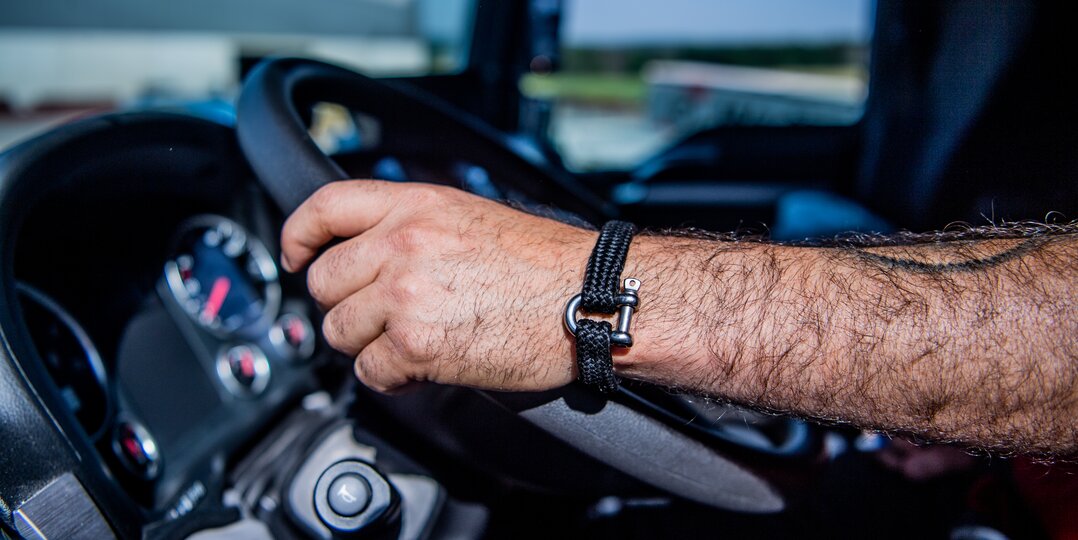 Hands of a delivery driver holding the steering wheel of a truck