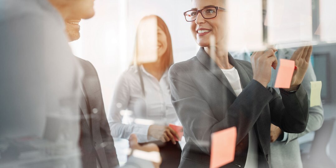 Woman in a meeting, sticking post-it notes and smiling