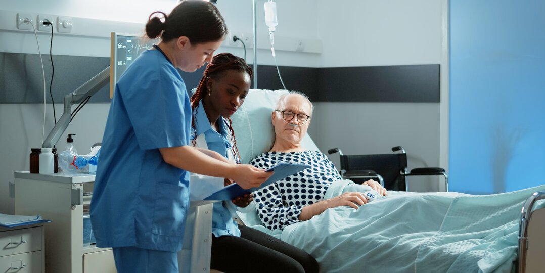 Dussmann Lavador laundry service meets the strict standards of the medical sector, guaranteeing optimal disinfection of hospital linens and impeccable quality for the protection of patients and nursing staff. | © <a href="https://www.freepik.com/free-photo/african-american-doctor-talking-sick-patient-bed-hospital-ward-treating-health-problems-injury-old-man-asking-medic-nurse-about-intensive-care-illness-recovery_20717490.htm">Image by DC Studio on Freepik</a>