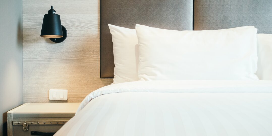 Dussmann laundry service for the hotel and food industry, providing clean, hygienic linen tailored to the requirements of these sectors, while complying with strict hygiene and quality protocols. | © <a href="https://www.freepik.com/free-photo/pillow-bed_1255051.htm#fromView=search&page=2&position=10&uuid=a7169df1-c8d3-4623-9cf3-a739261588af&query=pillow+on+hotel+bed">Image by mrsiraphol on Freepik</a>