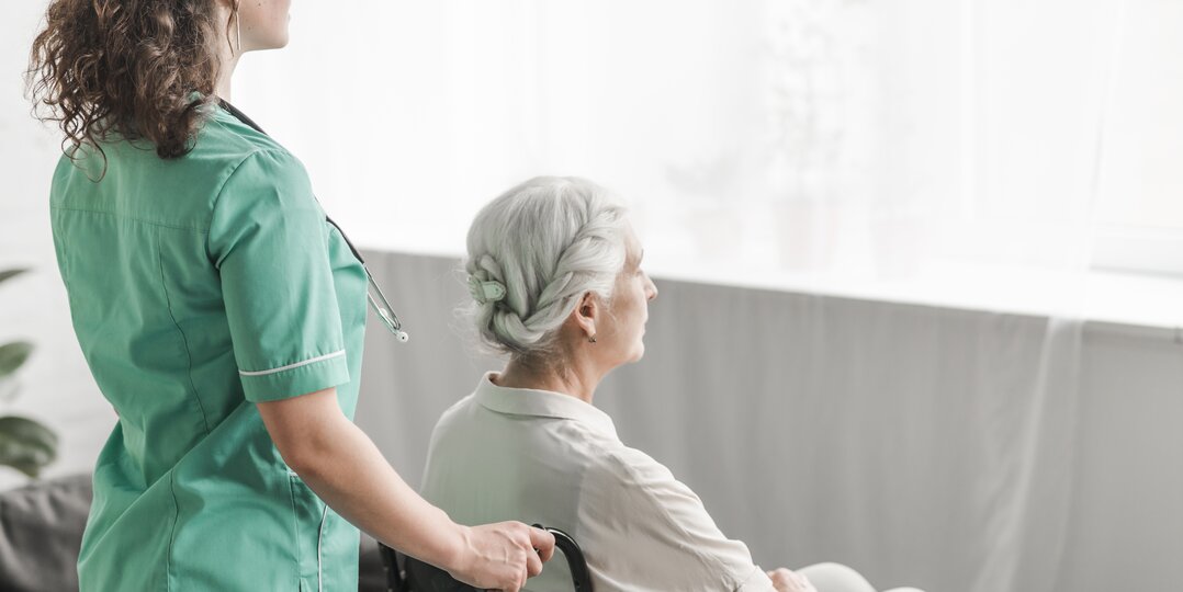 Dussmann laundry service for nursing homes, providing clean, soft and hygienic linen, adapted to the needs of residents, while complying with strict hygiene protocols for the well-being of the elderly | © <a href="https://www.freepik.com/free-photo/side-view-nurse-pushing-disabled-patient-wheel-chair_2652850.htm">Image by freepik</a>