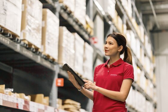 Woman in a stockroom with merchandise, using a tablet