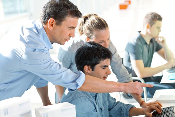 Man and woman collaborating with a young man on a computer