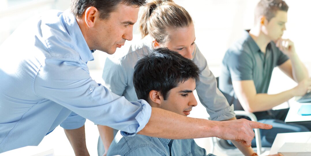 Man and woman collaborating with a young man on a computer