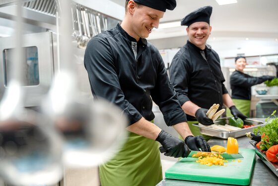 Two cooks chopping vegetables in a kitchen
