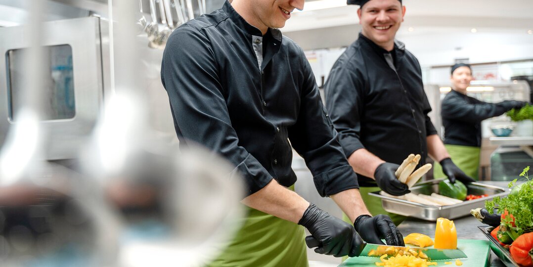 Two cooks chopping vegetables in a kitchen